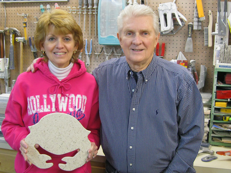 Colleen and Ed Herman stand in their cutting board workshop outside Millsboro. Colleen is holding a crab-shaped cutting board, which is one of the more popular designs. BY RACHEL SWICK MAVITY